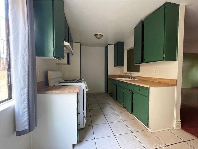 kitchen featuring sink, green cabinetry, butcher block countertops, white gas stove, and light tile patterned flooring