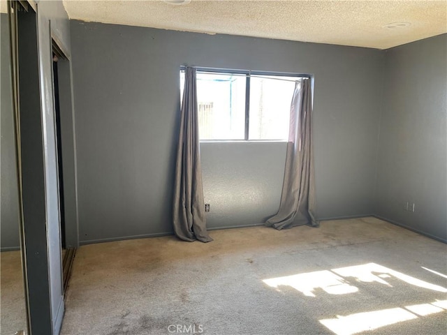 empty room with light colored carpet and a textured ceiling