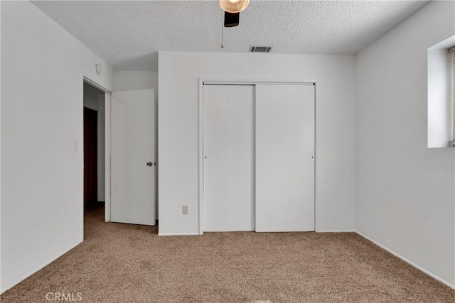 unfurnished bedroom with light carpet, a closet, ceiling fan, and a textured ceiling