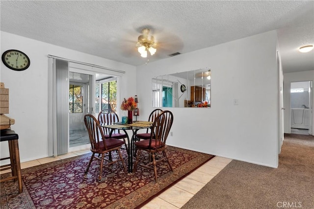 dining space with tile patterned flooring, ceiling fan, and a textured ceiling