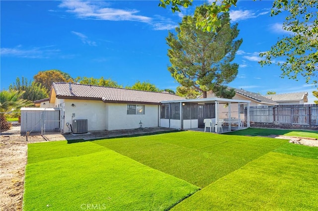 back of house with a sunroom, a lawn, and central AC