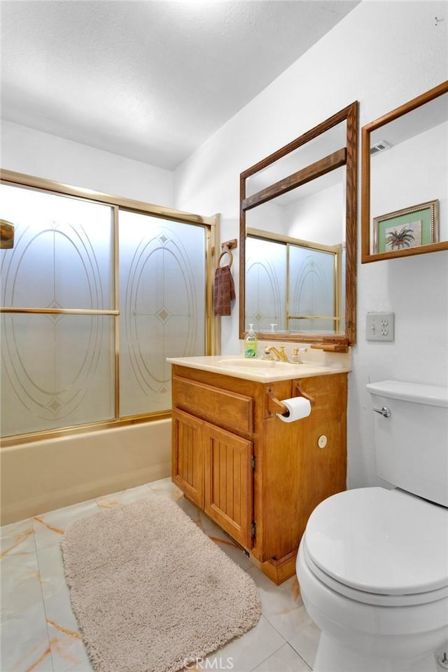 full bathroom featuring combined bath / shower with glass door, vanity, tile patterned floors, and toilet