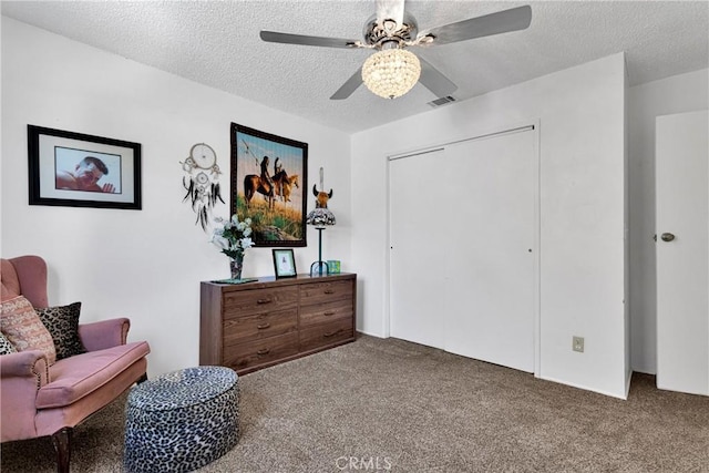 living area featuring ceiling fan, carpet floors, and a textured ceiling