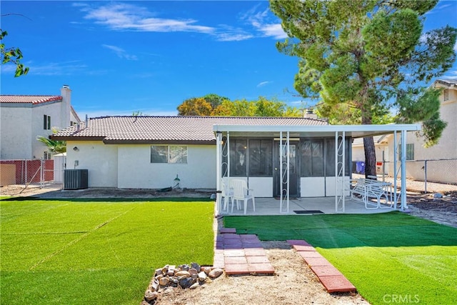 rear view of house featuring a sunroom, a patio, a lawn, and central AC