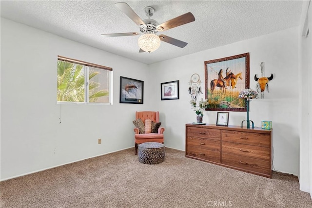 sitting room featuring ceiling fan, carpet floors, and a textured ceiling