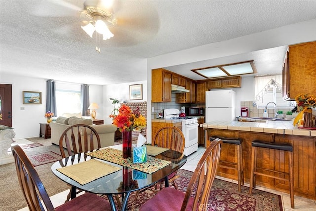 tiled dining room with ceiling fan, sink, and a textured ceiling