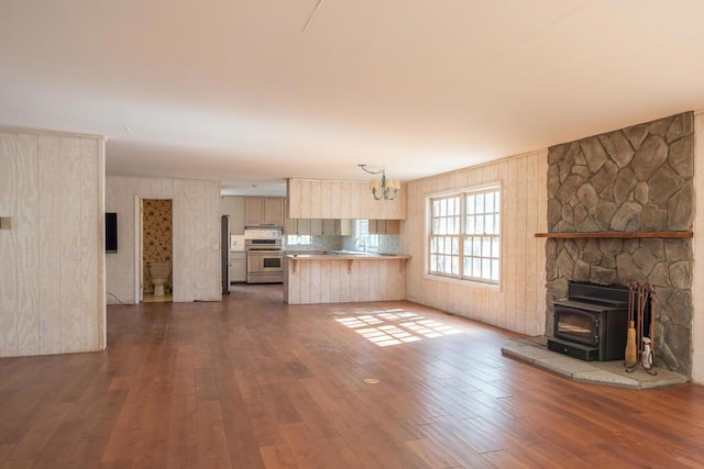 unfurnished living room featuring dark wood-type flooring, a wood stove, and sink