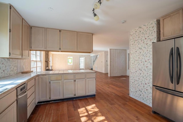 kitchen featuring tile counters, light hardwood / wood-style flooring, cream cabinets, and stainless steel refrigerator