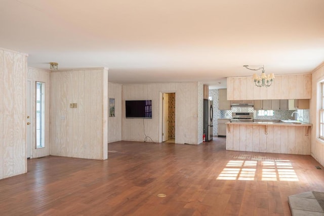 kitchen featuring tasteful backsplash, kitchen peninsula, sink, stainless steel fridge, and range