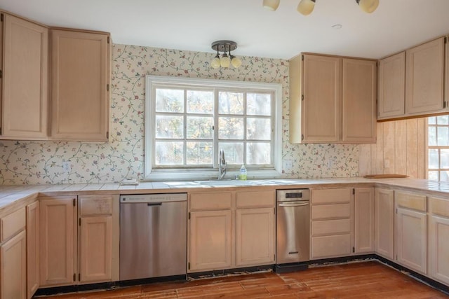 kitchen with tile counters, light brown cabinets, light hardwood / wood-style floors, sink, and stainless steel dishwasher