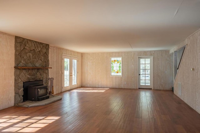 unfurnished living room featuring french doors, a wood stove, and hardwood / wood-style flooring