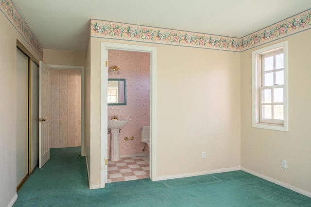 unfurnished bedroom featuring carpet floors, sink, and ensuite bath