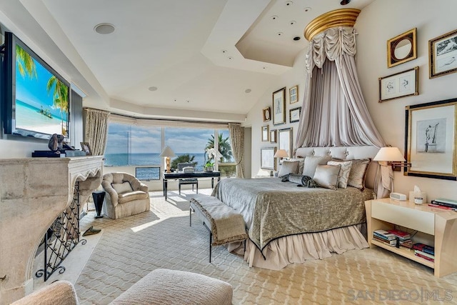 bedroom featuring a water view, lofted ceiling, and light carpet