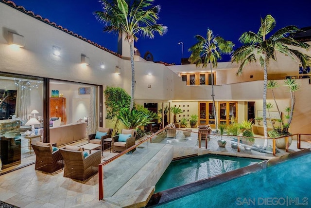 pool at night featuring a patio area and an outdoor living space