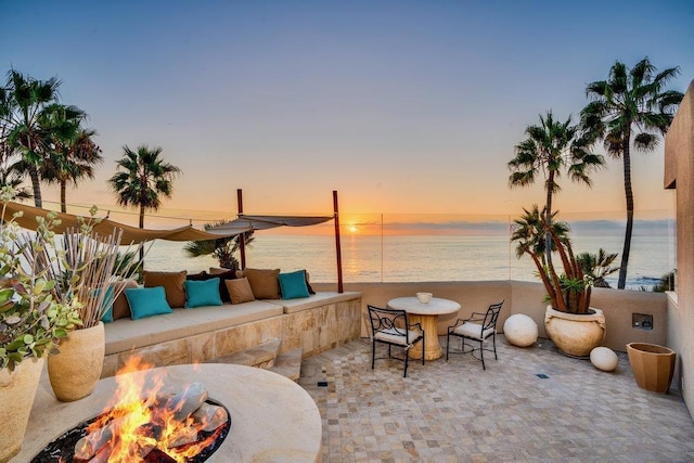 patio terrace at dusk with a water view and an outdoor living space with a fire pit