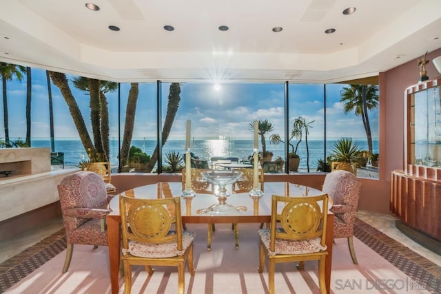 sunroom / solarium featuring a raised ceiling, a water view, and a wealth of natural light