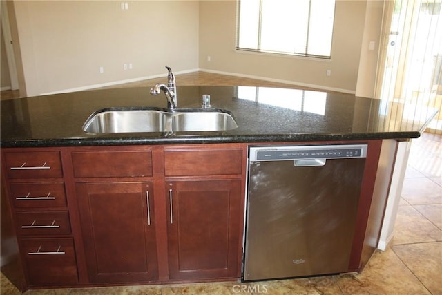 kitchen featuring stainless steel dishwasher, light tile patterned floors, sink, and dark stone counters