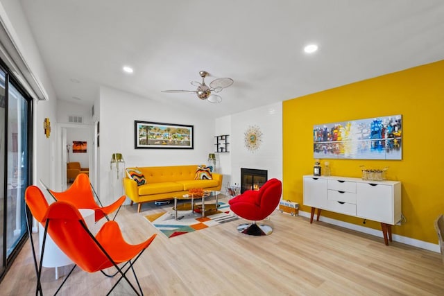 sitting room with ceiling fan, a fireplace, and light hardwood / wood-style flooring