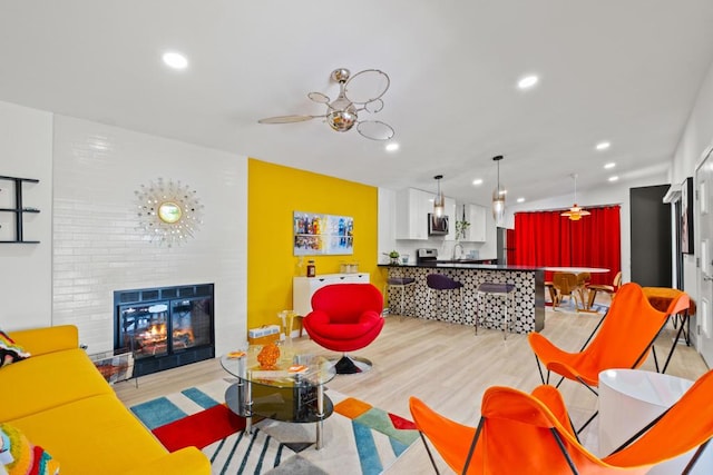 living room featuring ceiling fan, light hardwood / wood-style floors, a fireplace, and sink