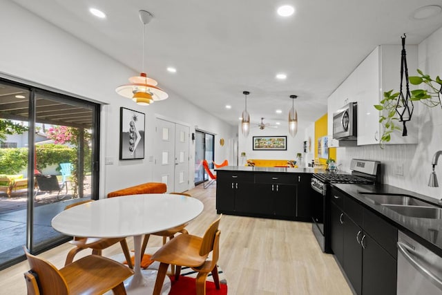 kitchen with decorative light fixtures, ceiling fan, sink, light wood-type flooring, and stainless steel appliances