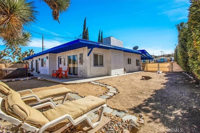 rear view of house featuring a patio area and a hot tub