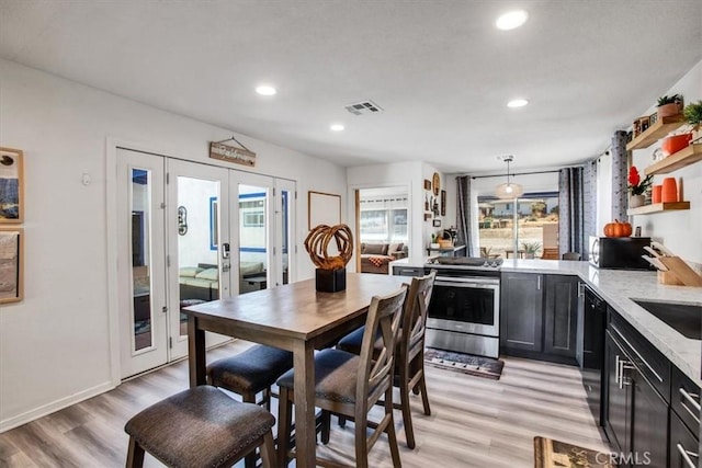 kitchen featuring light stone countertops, decorative light fixtures, light hardwood / wood-style floors, and black appliances