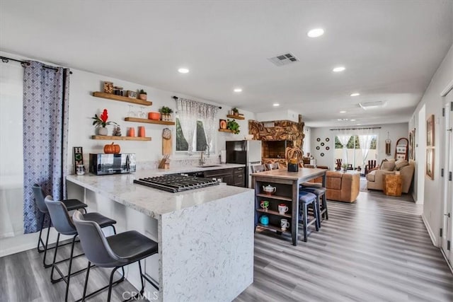 kitchen featuring hardwood / wood-style floors, kitchen peninsula, sink, and appliances with stainless steel finishes