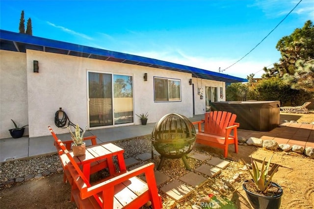 rear view of property featuring a patio and a hot tub