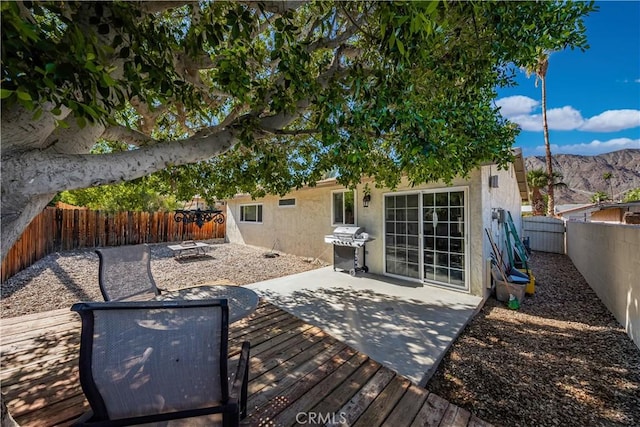 wooden terrace featuring grilling area, an outdoor fire pit, a mountain view, and a patio area