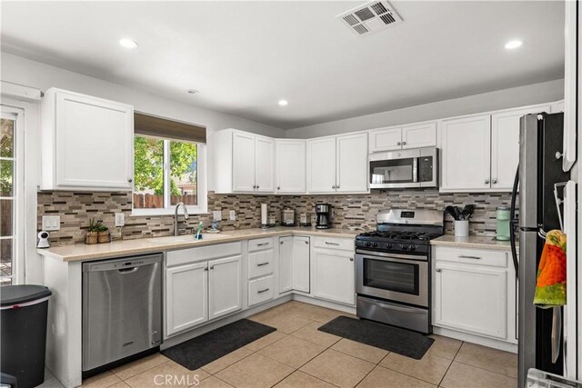 kitchen with appliances with stainless steel finishes, backsplash, white cabinetry, and sink