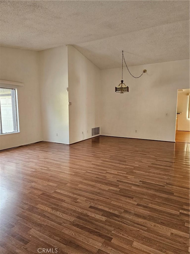 spare room featuring a textured ceiling, a chandelier, and dark hardwood / wood-style floors