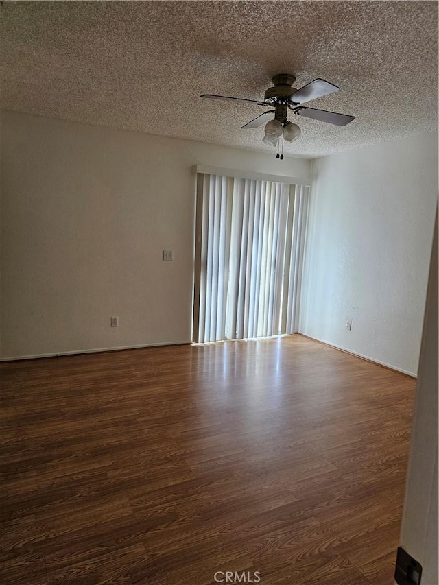 empty room with dark hardwood / wood-style floors, ceiling fan, and a textured ceiling