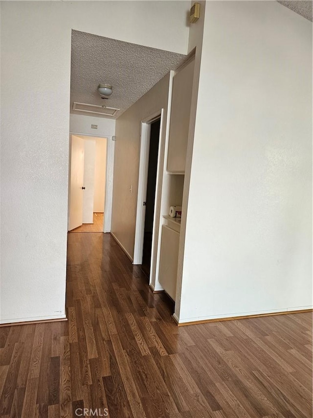 hallway with a textured ceiling and dark wood-type flooring