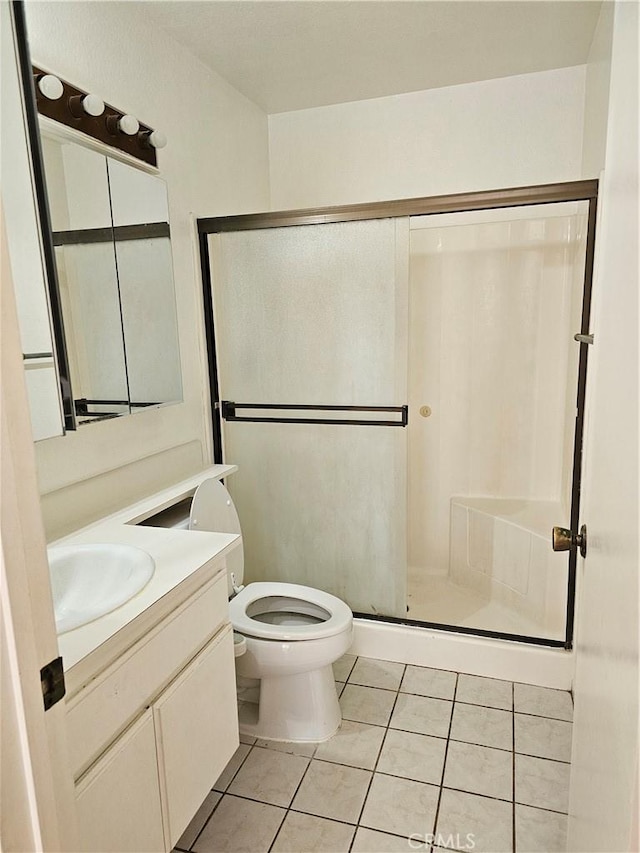 bathroom with toilet, vanity, tile patterned floors, and an enclosed shower