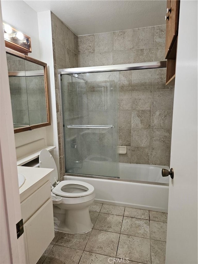 full bathroom featuring vanity, combined bath / shower with glass door, tile patterned flooring, toilet, and a textured ceiling