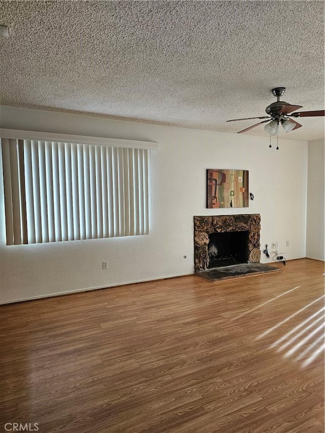 unfurnished living room with a textured ceiling, hardwood / wood-style flooring, and ceiling fan