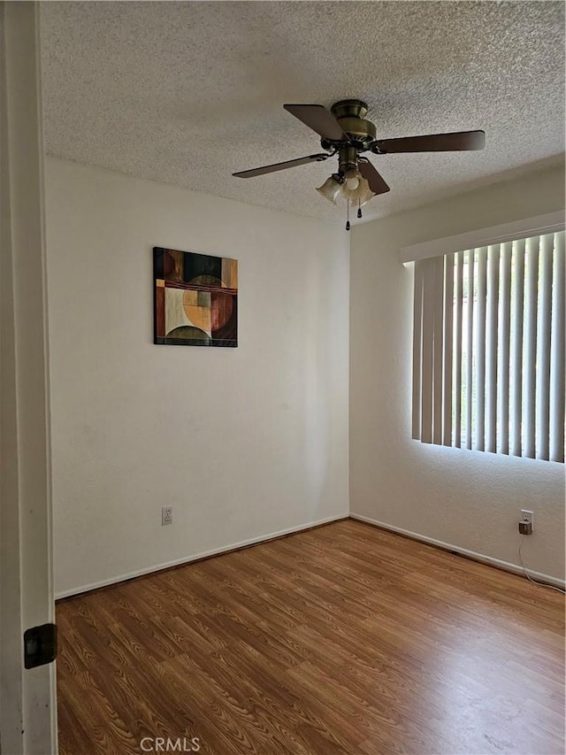 spare room featuring ceiling fan, wood-type flooring, and a textured ceiling