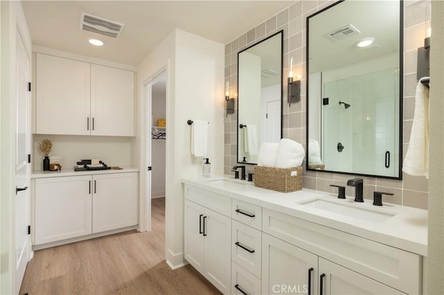 bathroom featuring decorative backsplash, vanity, a shower with shower door, and hardwood / wood-style flooring