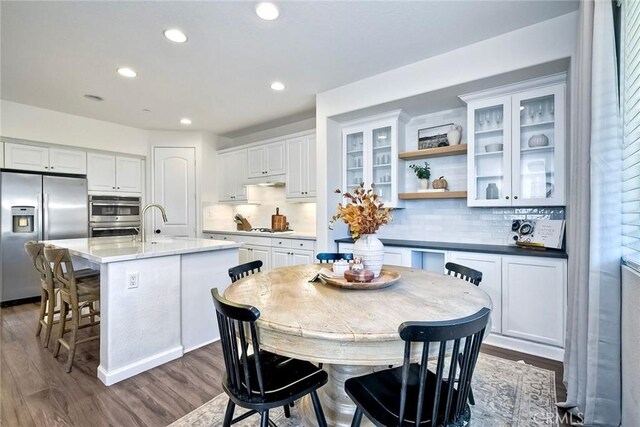 kitchen featuring stainless steel appliances, an island with sink, white cabinets, and decorative backsplash