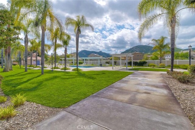 surrounding community featuring a mountain view, a pergola, a lawn, and a swimming pool