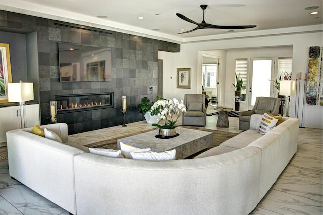 living room with ceiling fan, tile walls, and a tile fireplace