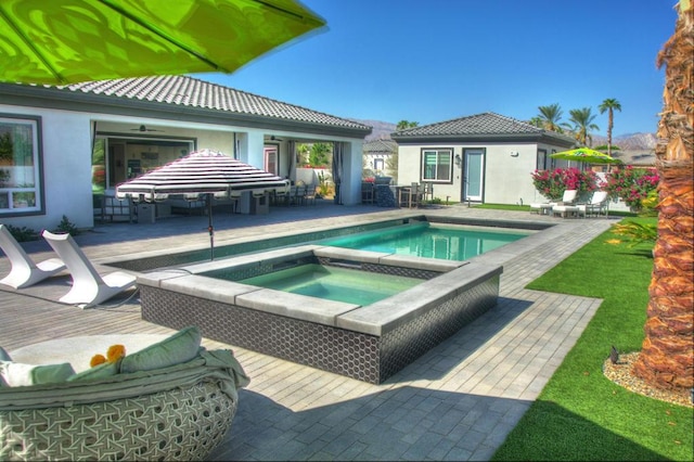 view of pool with an in ground hot tub, a patio area, and an outbuilding