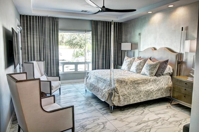 bedroom featuring ceiling fan, multiple windows, and a raised ceiling