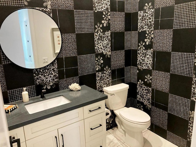 bathroom with tile walls, toilet, vanity, and tasteful backsplash