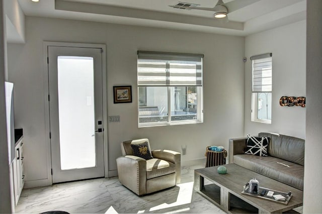 living room with ceiling fan and a raised ceiling