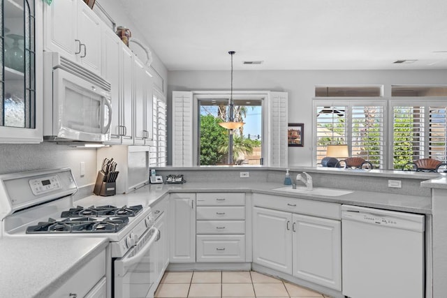 kitchen featuring white appliances, hanging light fixtures, sink, light tile patterned floors, and white cabinetry