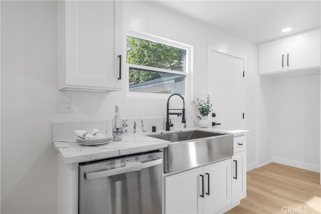 kitchen with white cabinets, stainless steel dishwasher, light stone countertops, and sink