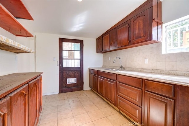 kitchen with plenty of natural light, light tile patterned floors, sink, and tasteful backsplash