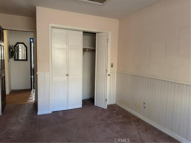 unfurnished bedroom featuring a closet and dark colored carpet