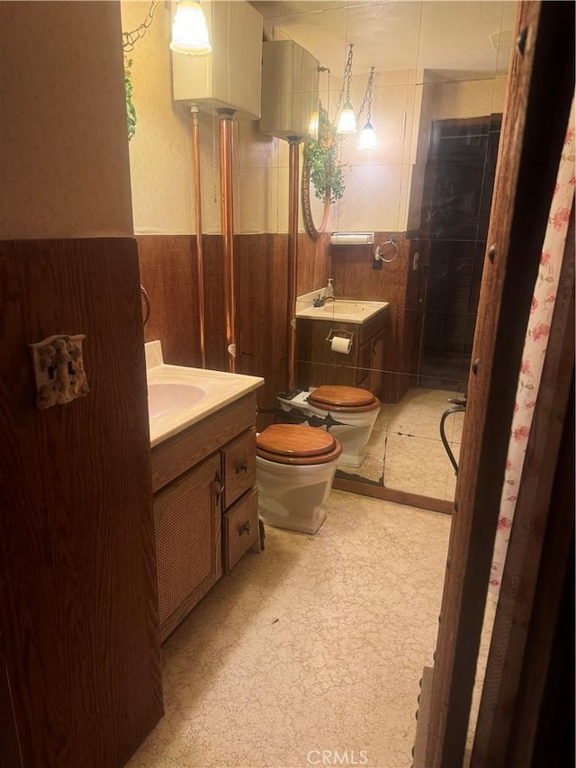 bathroom featuring vanity, toilet, tile walls, and a bidet